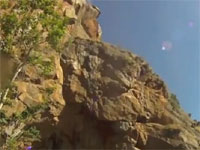 崖飛び込みに失敗して途中の岩肌に激突してしまう少年の映像。