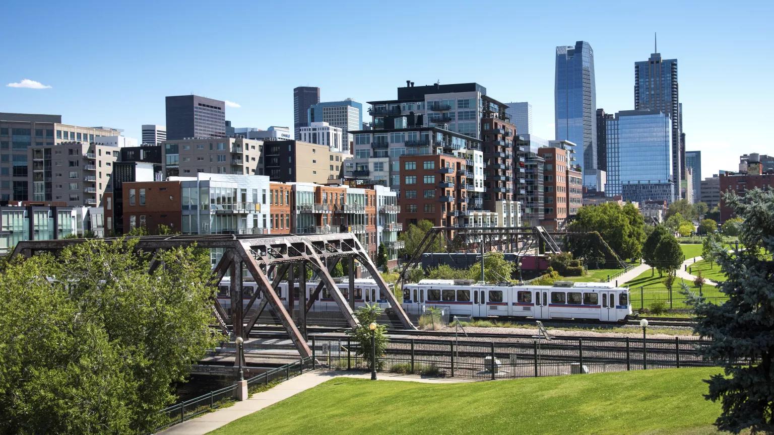 A cityscape view of the lower downtown district of Denver, with the light rail train in the forefront