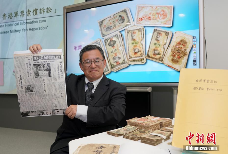 「香港軍票訴訟」関連の歴史資料を見せる和仁廉夫氏 (撮影・張■、■は火へんに韋)。