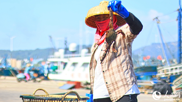 採れたてのカニを、満面の笑みを浮かべながら見せる澳角村の女性（撮影・李昌乾）。