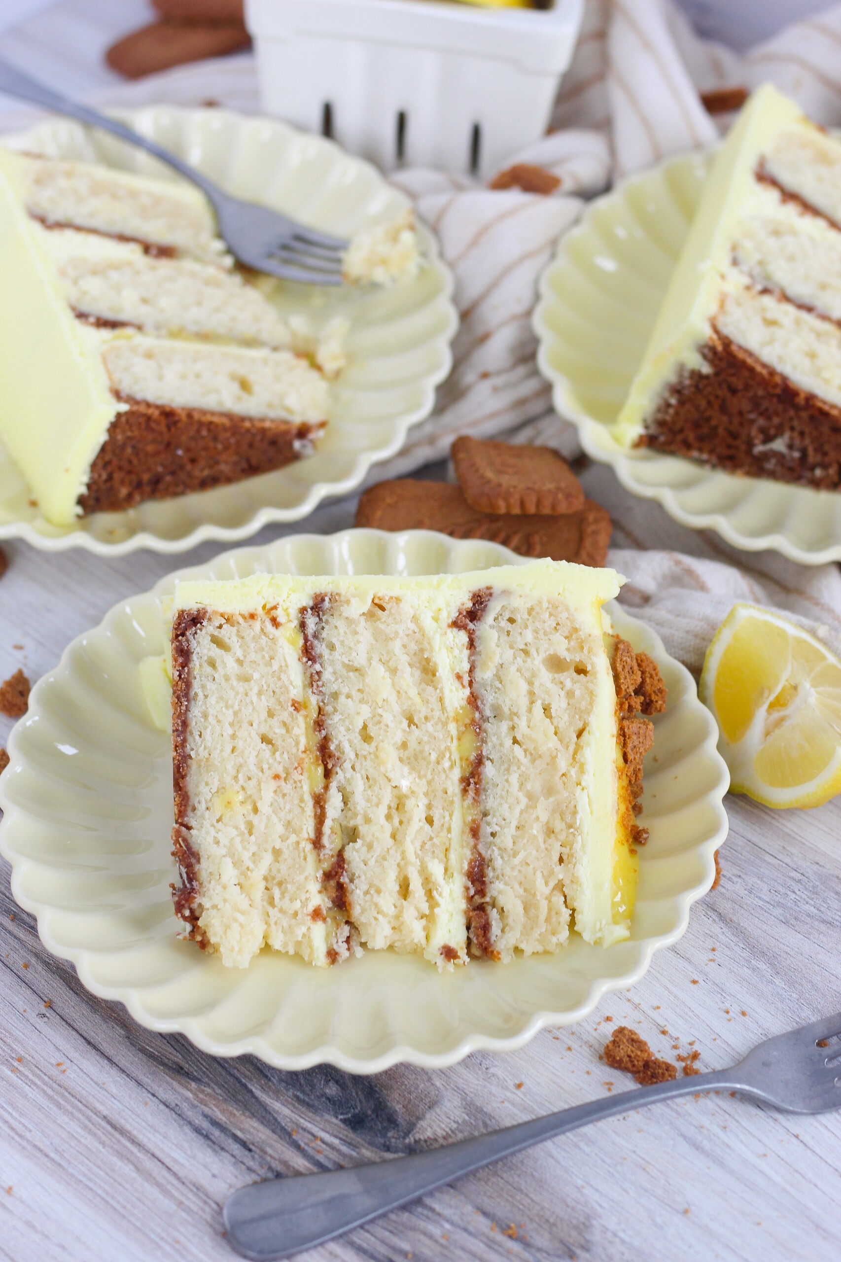 Slice of cake on a plate with lemons and cookies.