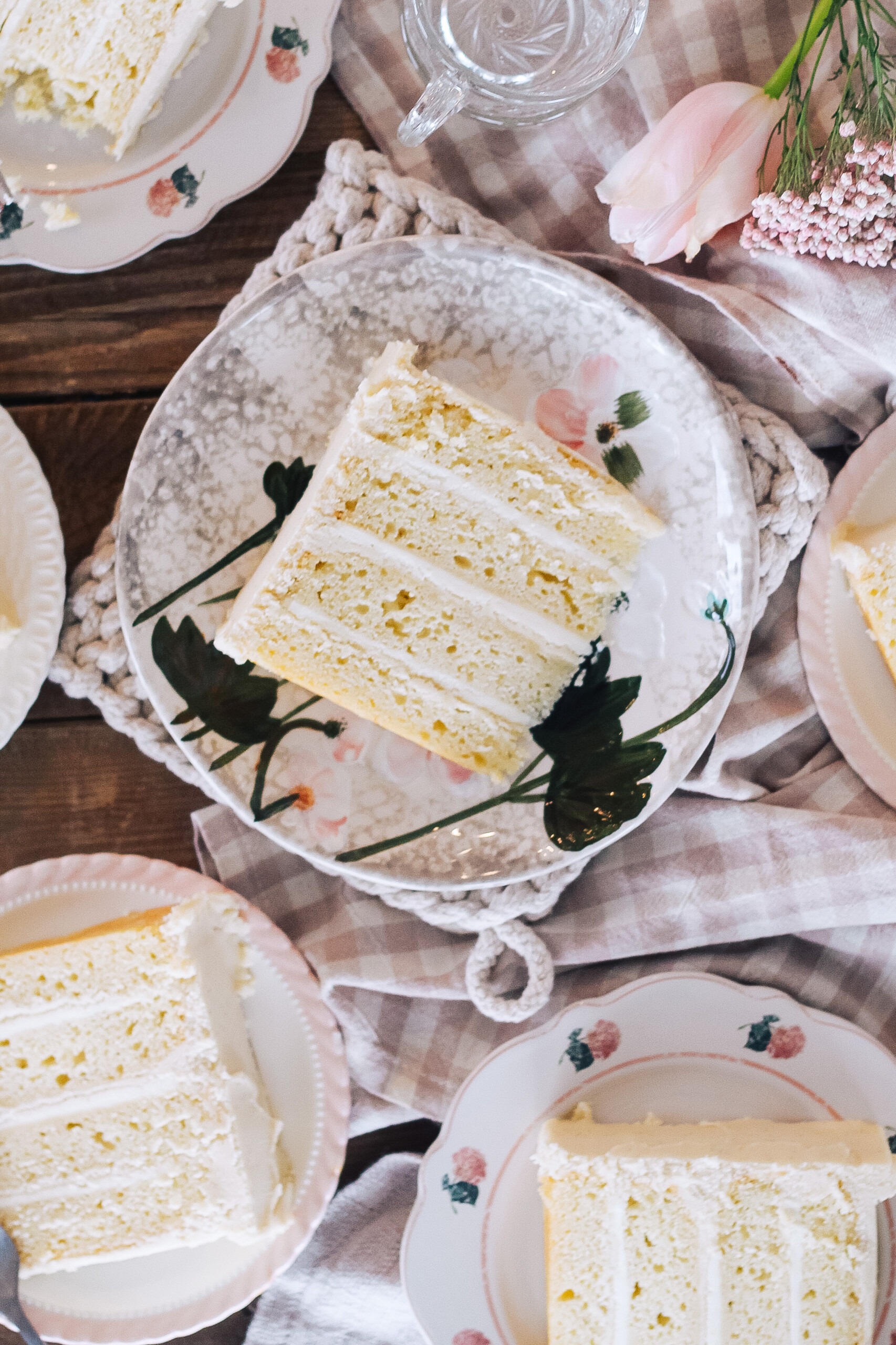 A slice of a four layer cake on a floral designed plate.