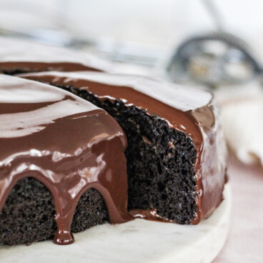 A slice of chocolate cake taken out of a full cake.