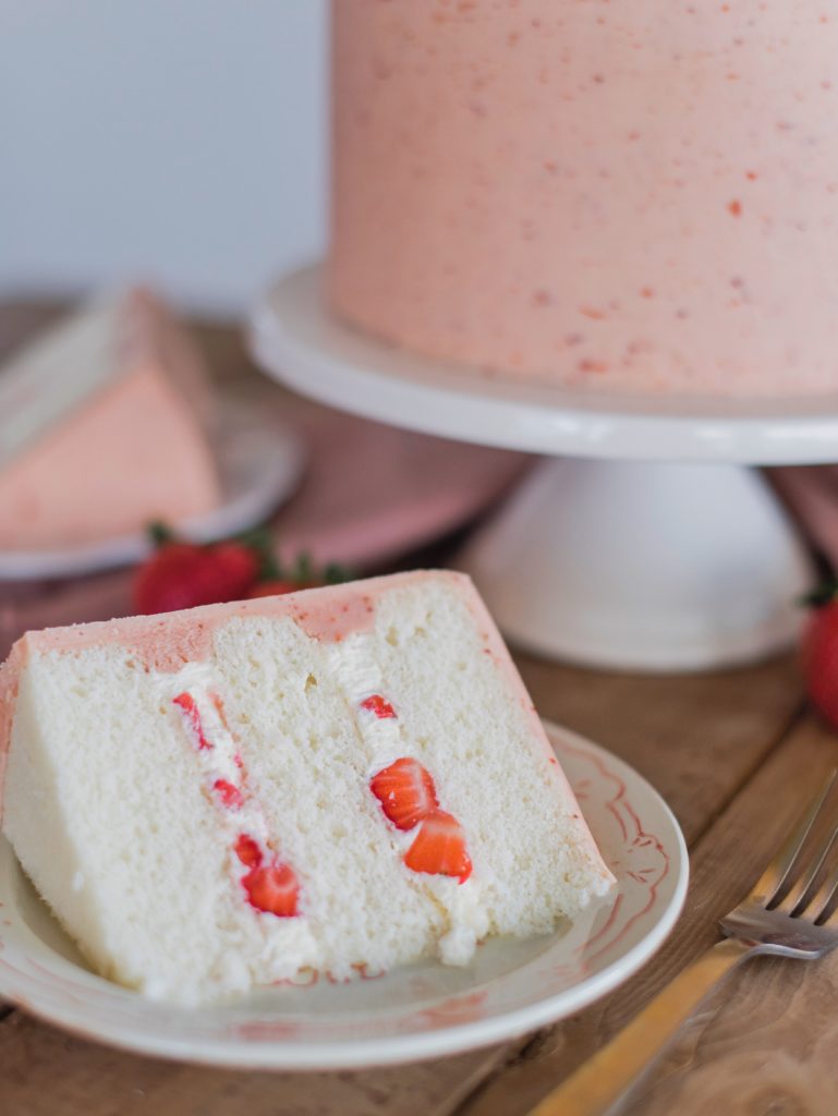 Strawberry Shortcake: Tender and fluffy layers of vanilla cake, filled with whipped cream and fresh strawberries, and covered in a strawberry buttercream. #cakebycourtney #cake #cakerecipe #strawberryshortcake #shortcake #strawberry #buttercream