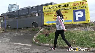 Straight haired emo chick pulls down black jeans to pee at the bus parking